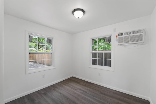 empty room with baseboards, dark wood-style flooring, and an AC wall unit