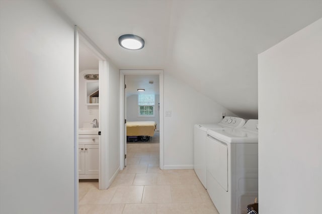 laundry area with light tile patterned floors, baseboards, a sink, and washing machine and clothes dryer