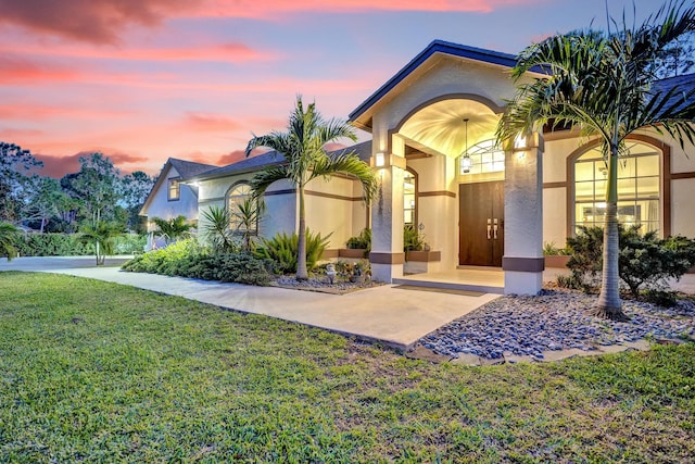 entrance to property featuring a yard and stucco siding