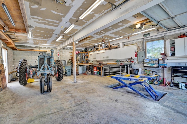 garage with a garage door opener, concrete block wall, and a workshop area