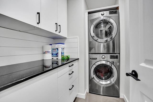 washroom with cabinet space and stacked washer and clothes dryer