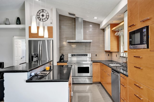 kitchen featuring a kitchen island, a sink, appliances with stainless steel finishes, backsplash, and wall chimney exhaust hood