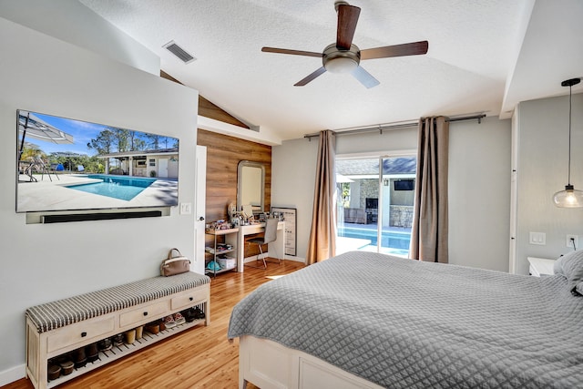 bedroom featuring a textured ceiling, wood finished floors, visible vents, vaulted ceiling, and access to outside