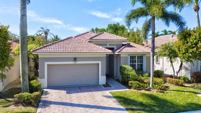 mediterranean / spanish house with an attached garage, a tiled roof, decorative driveway, and stucco siding