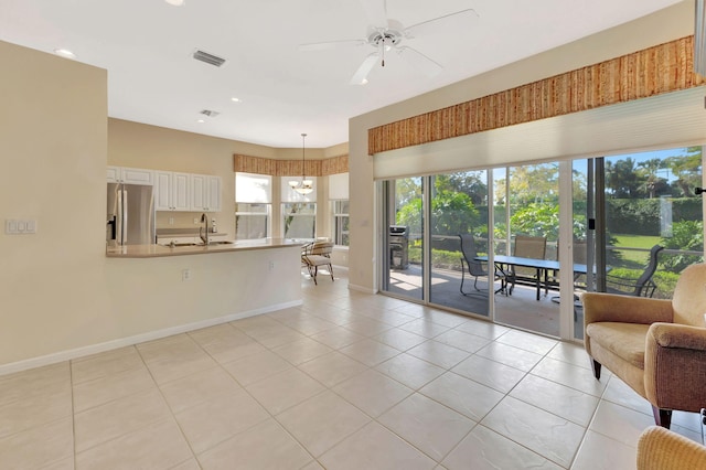 living room featuring light tile patterned floors, ceiling fan with notable chandelier, visible vents, and baseboards