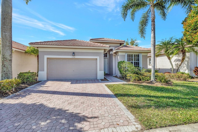 mediterranean / spanish home featuring a garage, a tile roof, decorative driveway, a front lawn, and stucco siding