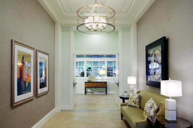 corridor with wood finished floors, a raised ceiling, baseboards, and an inviting chandelier