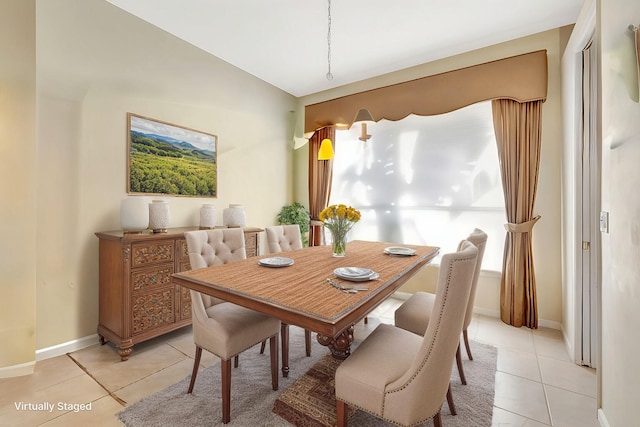 dining area featuring light tile patterned floors, baseboards, and vaulted ceiling