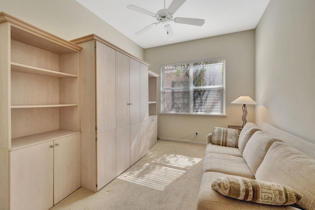 living area featuring light colored carpet, ceiling fan, and baseboards