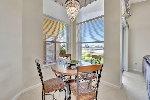 dining area featuring an inviting chandelier, baseboards, and light tile patterned flooring