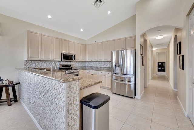 kitchen with light stone counters, a peninsula, visible vents, appliances with stainless steel finishes, and tasteful backsplash