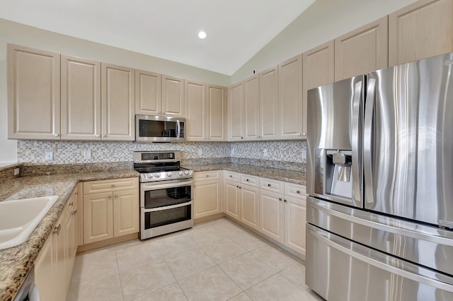 kitchen with lofted ceiling, light tile patterned floors, appliances with stainless steel finishes, and decorative backsplash