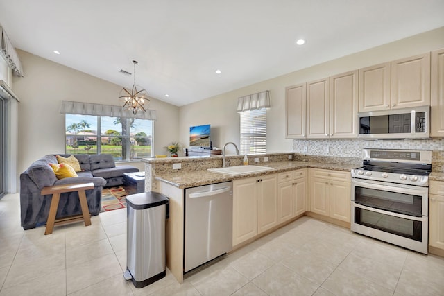 kitchen with stainless steel appliances, open floor plan, a healthy amount of sunlight, a sink, and a peninsula