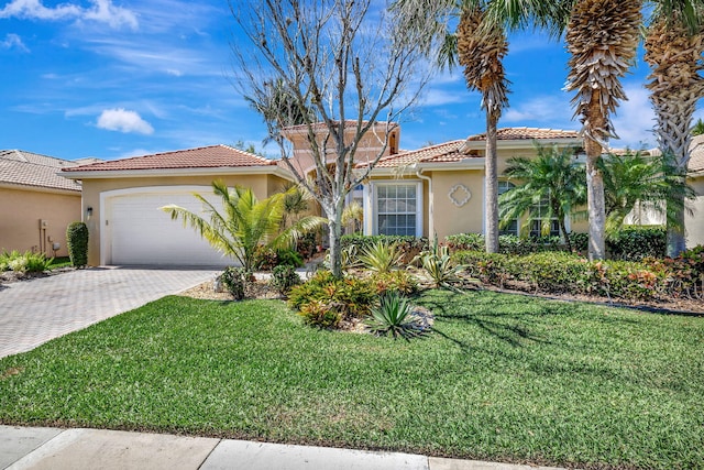 mediterranean / spanish-style house with a garage, a front yard, decorative driveway, and stucco siding