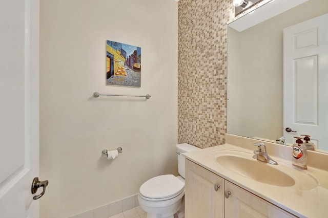 half bathroom featuring baseboards, vanity, toilet, and tile patterned floors