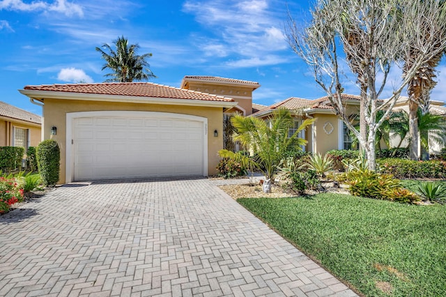 mediterranean / spanish-style house featuring a garage, a tiled roof, decorative driveway, and stucco siding