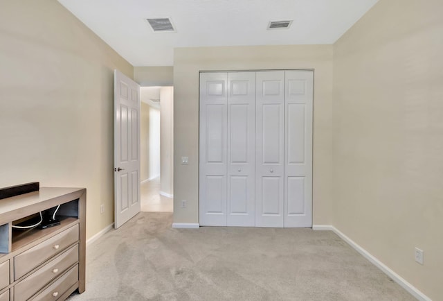 unfurnished bedroom featuring baseboards, visible vents, a closet, and light colored carpet