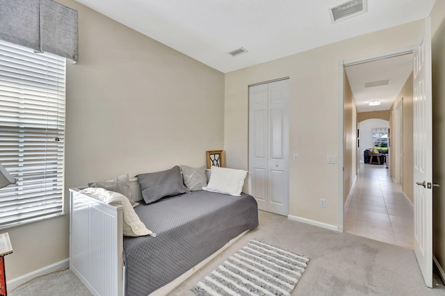 bedroom featuring visible vents, arched walkways, a closet, and light colored carpet