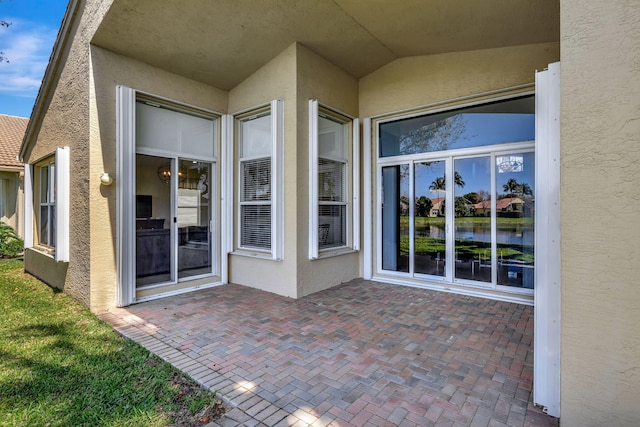 view of exterior entry featuring a patio area and stucco siding