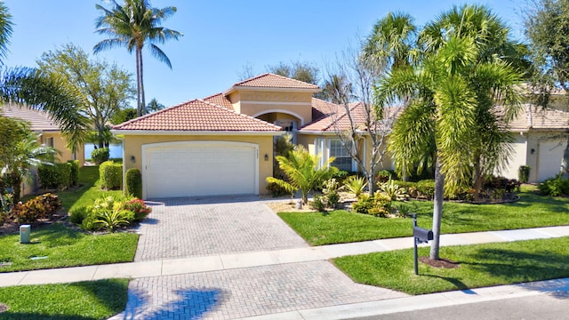 mediterranean / spanish-style home featuring a tile roof, an attached garage, decorative driveway, a front lawn, and stucco siding