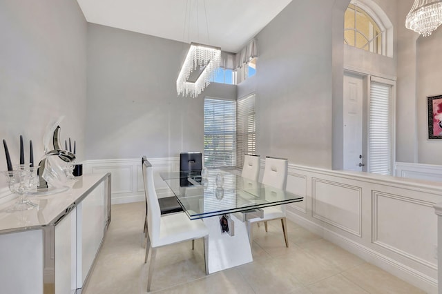 dining room featuring light tile patterned floors, a decorative wall, a towering ceiling, and a notable chandelier