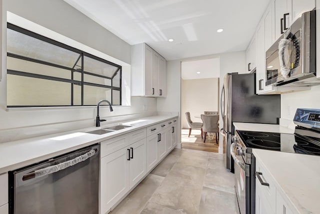 kitchen featuring recessed lighting, a sink, stainless steel appliances, light countertops, and white cabinetry