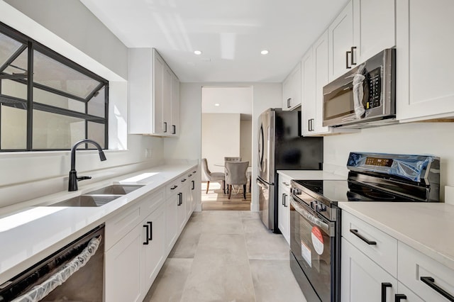 kitchen featuring white cabinetry, light countertops, appliances with stainless steel finishes, and a sink