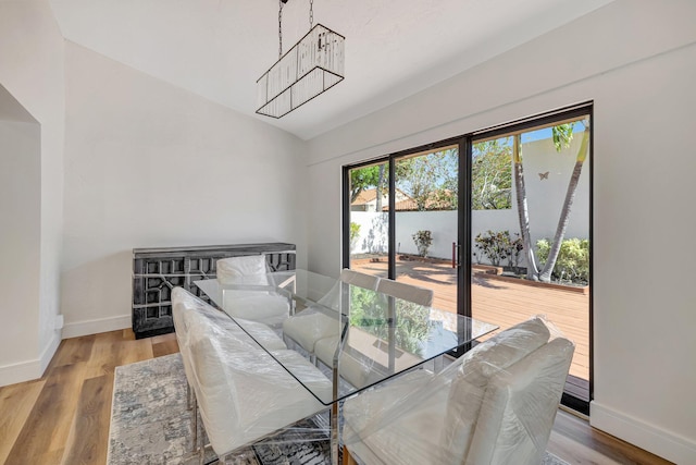 dining area with baseboards, lofted ceiling, and light wood-style flooring