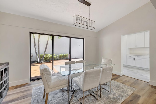 dining area with baseboards, an inviting chandelier, light wood-style flooring, and vaulted ceiling