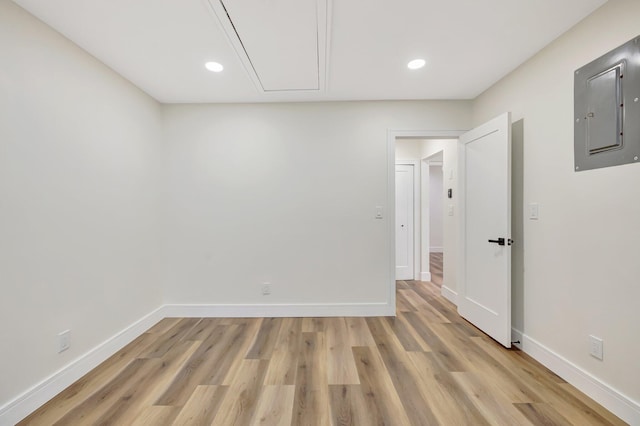 spare room with baseboards, attic access, light wood-style flooring, electric panel, and recessed lighting