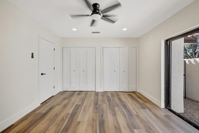 unfurnished bedroom with visible vents, light wood-style flooring, two closets, and baseboards