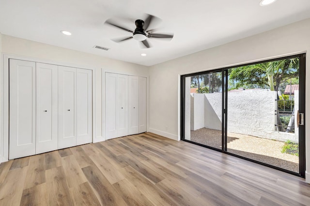 unfurnished bedroom with access to exterior, visible vents, two closets, light wood-style flooring, and recessed lighting