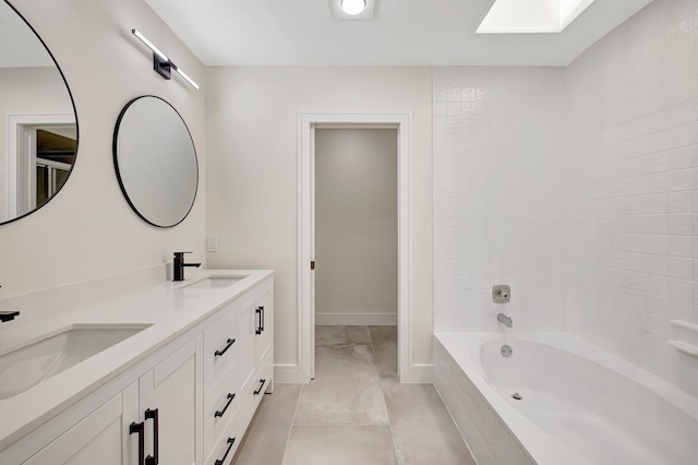 full bath featuring a sink, baseboards, a skylight, and double vanity