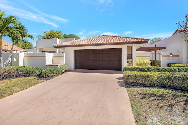 mediterranean / spanish home with fence, a tiled roof, stucco siding, a garage, and driveway