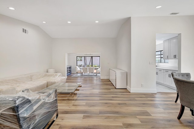 living room with recessed lighting, light wood-style flooring, and vaulted ceiling