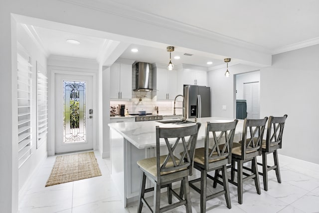 kitchen featuring stove, a sink, marble finish floor, stainless steel fridge with ice dispenser, and wall chimney exhaust hood