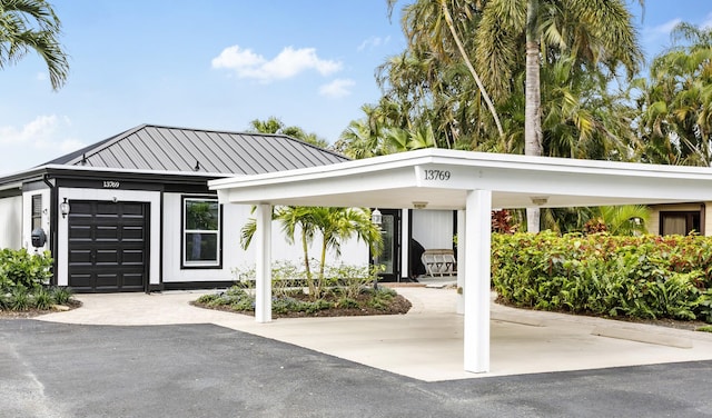 view of front of home with a standing seam roof, metal roof, driveway, and an attached garage