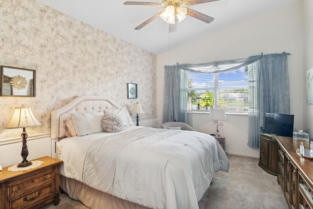 bedroom featuring ceiling fan, light carpet, baseboards, vaulted ceiling, and wallpapered walls