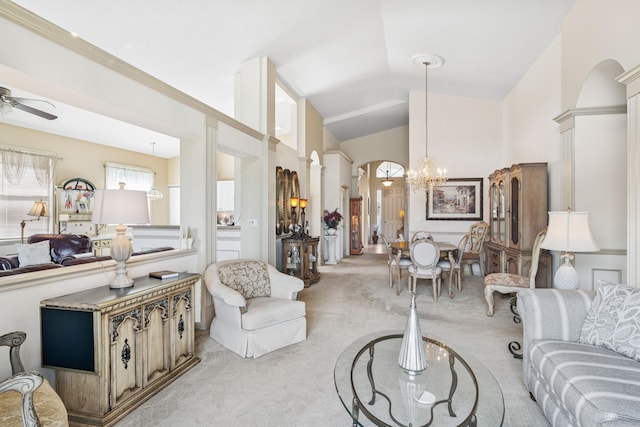 carpeted living room featuring lofted ceiling, ornate columns, arched walkways, and ceiling fan with notable chandelier