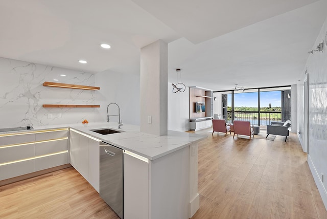 kitchen featuring a wall of windows, open shelves, light stone countertops, a sink, and light wood-style flooring
