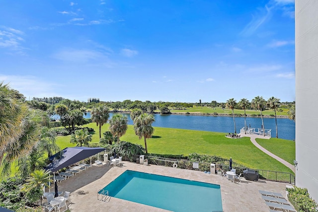 community pool featuring a lawn, a patio, a water view, and fence private yard