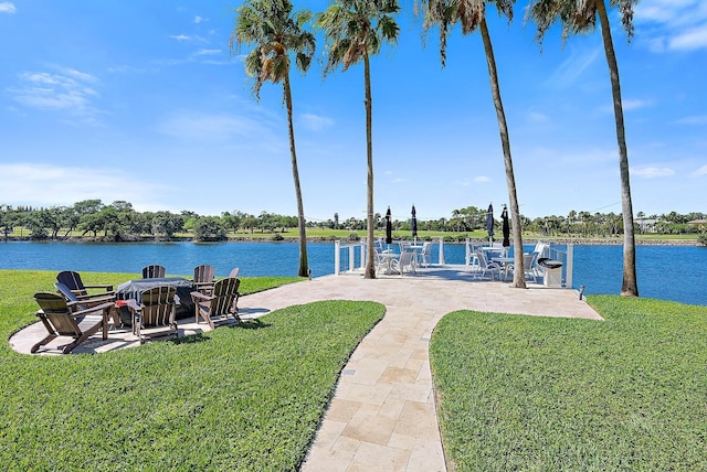 view of dock with a lawn, a water view, and a patio