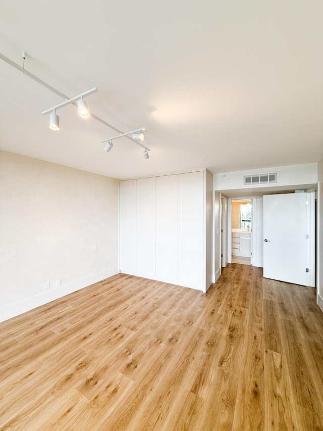 unfurnished room featuring track lighting, baseboards, light wood-style flooring, and visible vents