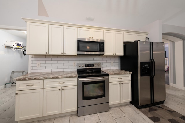 kitchen with appliances with stainless steel finishes, visible vents, backsplash, and light stone counters