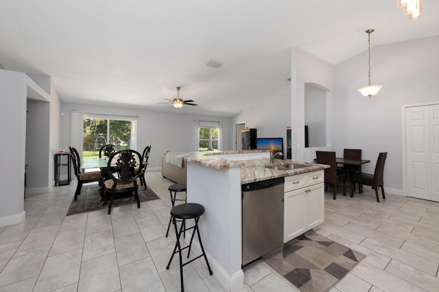 kitchen with light stone counters, vaulted ceiling, stainless steel dishwasher, pendant lighting, and a sink