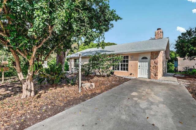 single story home featuring a chimney and stucco siding