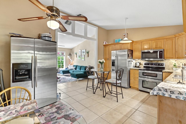 kitchen with stainless steel appliances, light countertops, vaulted ceiling, and light tile patterned floors