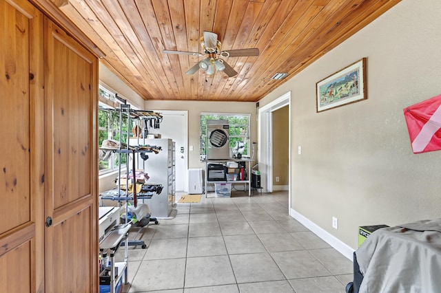 exercise area with ceiling fan, light tile patterned flooring, wooden ceiling, and baseboards