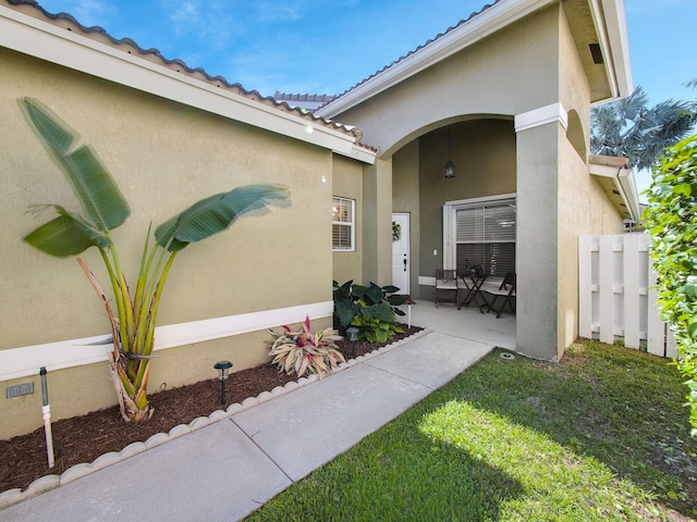 property entrance with a tile roof, a patio, and stucco siding