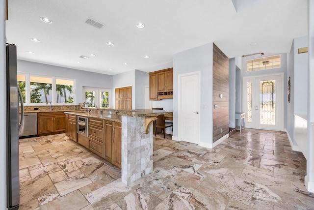 kitchen featuring appliances with stainless steel finishes, a wealth of natural light, brown cabinetry, and visible vents